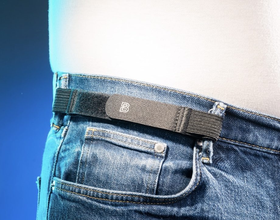 Sick woman tightening her waist with belt on dark background